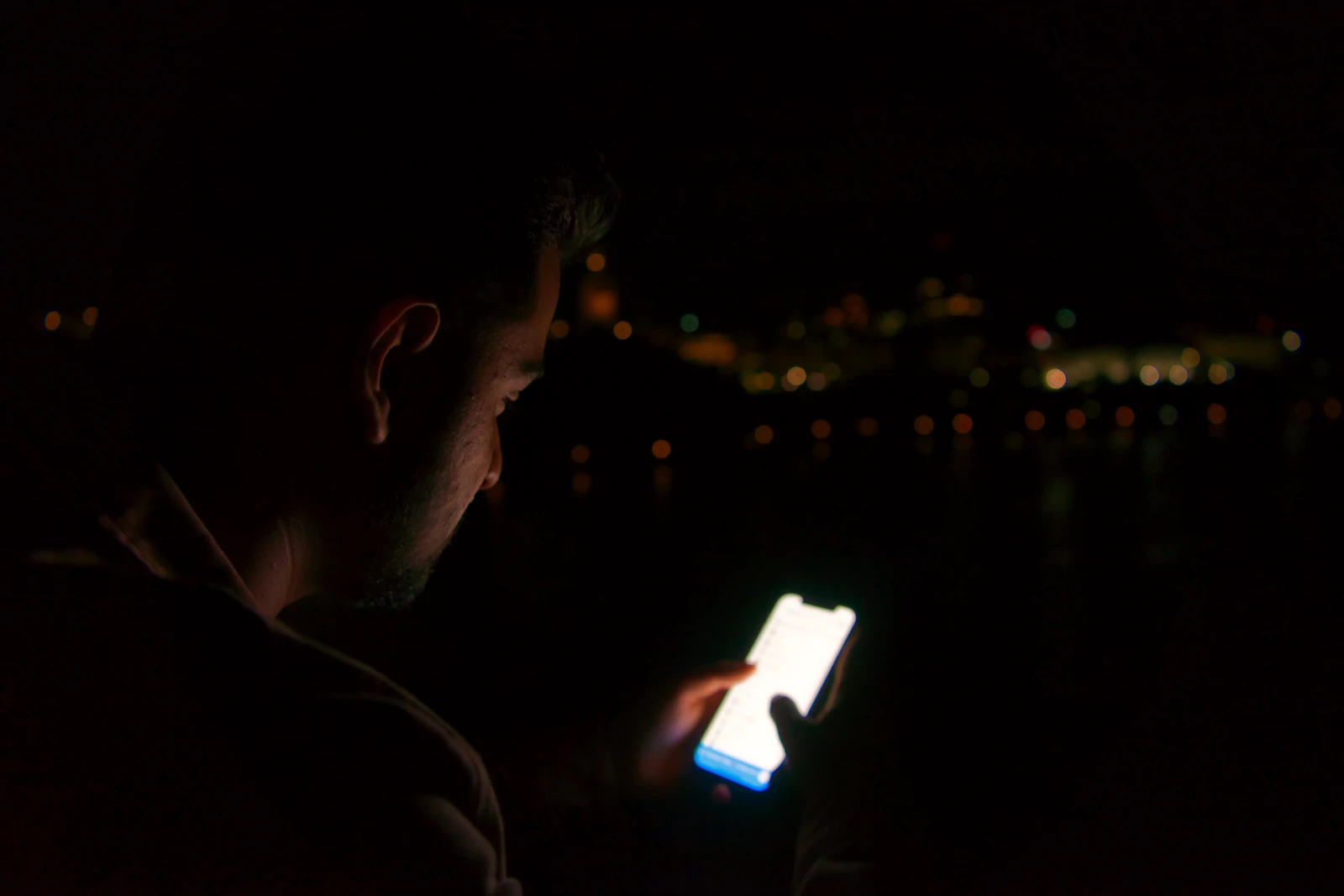 Personne qui consulte son téléphone le soir